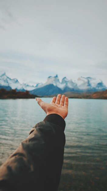 Zdjęcie przycięta ręka gestującą na jeziorze
