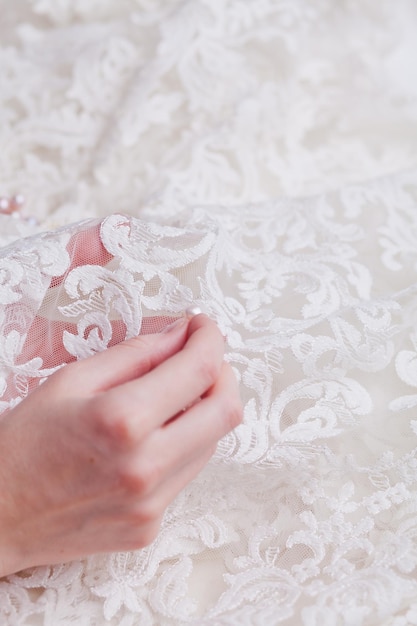 Zdjęcie przycięta ręka kobiety szyjącej perły na białej sukni ślubnej