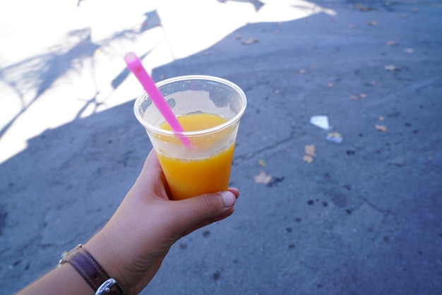 Przycięta ręka kobiety trzymającej drinka na ulicy
