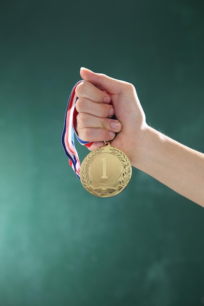 Przycięta ręka kobiety trzymającej medal na ścianie