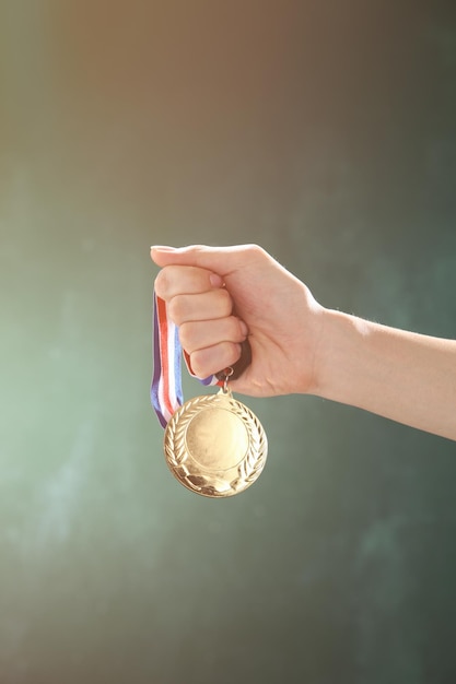 Przycięta ręka kobiety trzymającej medal na ścianie