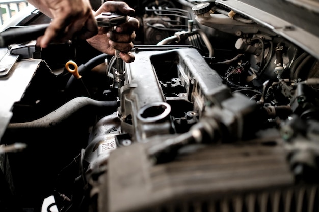 Przycięta ręka mechanika naprawiającego samochód w garażu