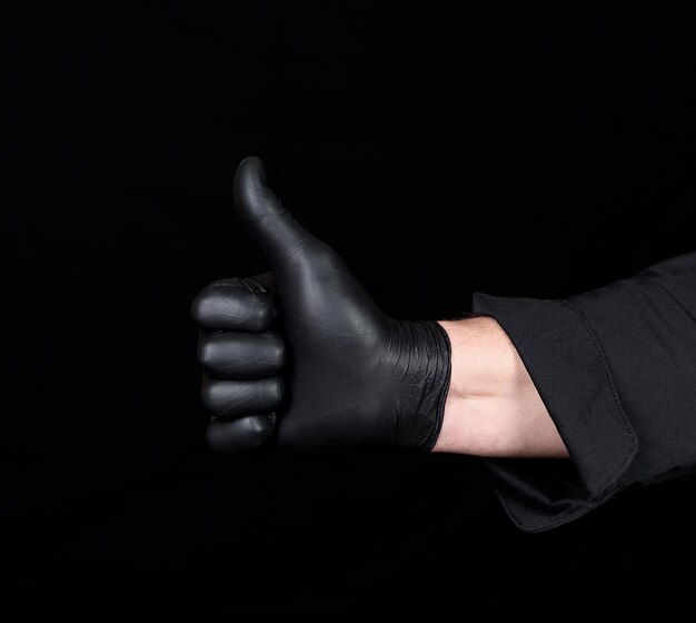 Zdjęcie przycięta ręka mężczyzny w rękawiczce wskazująca kciukiem w górę na czarnym tle