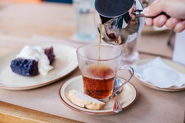 Przycięta ręka nalewająca drinka do kubka na stole