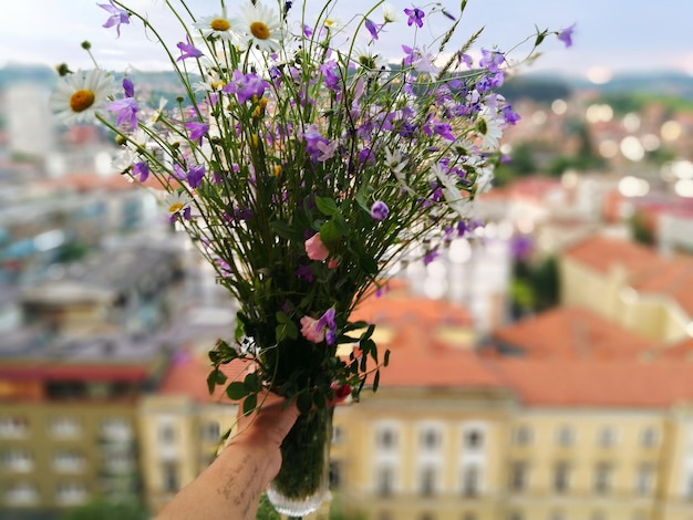 Zdjęcie przycięta ręka osoby trzymającej bukiet w mieście