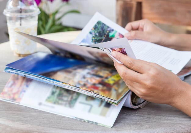 Zdjęcie przycięta ręka osoby trzymającej czasopismo na stole