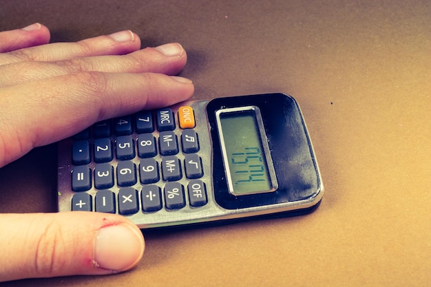 Zdjęcie przycięta ręka osoby trzymającej kalkulator na stole