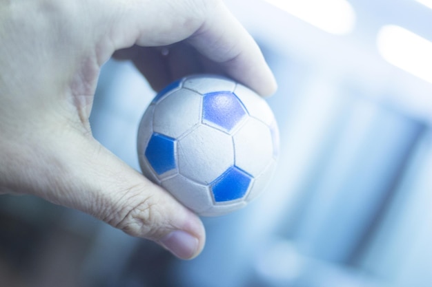 Zdjęcie przycięta ręka osoby trzymającej małą piłkę piłkarską w domu