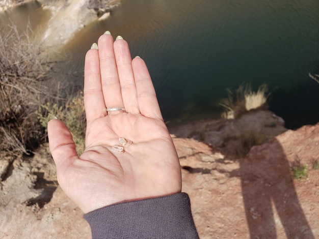 Zdjęcie przycięta ręka osoby trzymającej skałę nad jeziorem