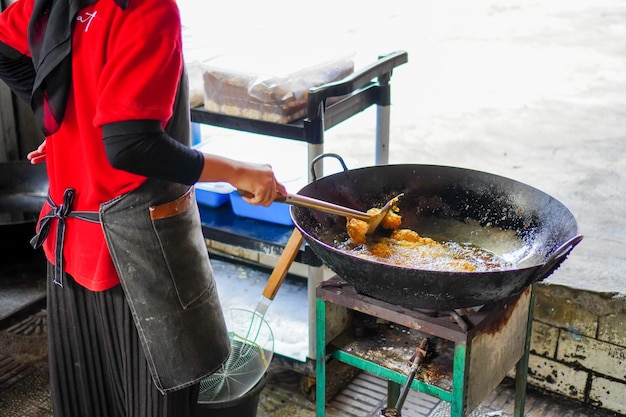 Przycięta ręka przygotowująca smażone tofu w kuchni Gotowanie na ogniu