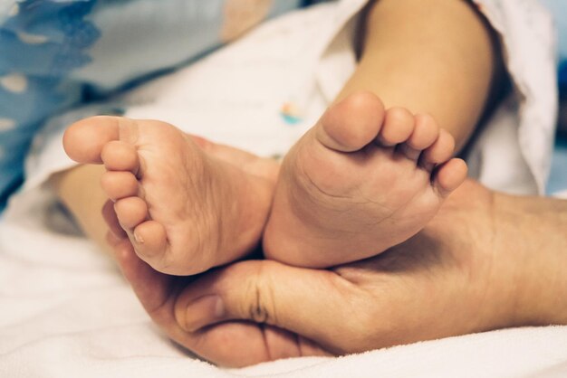 Zdjęcie przycięta ręka trzymająca nogi dziecka