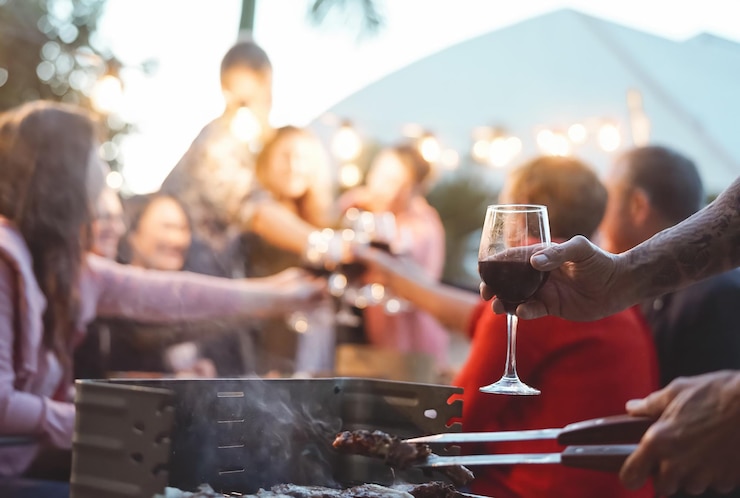 Zdjęcie przycięta ręka trzymająca szklankę do picia podczas gotowania jedzenia na grillu