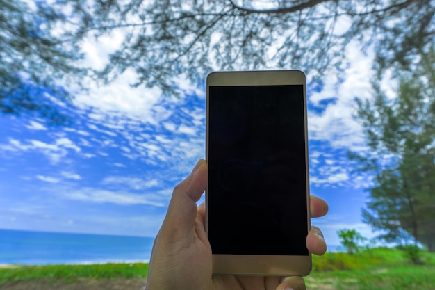 Zdjęcie przycięta ręka trzymająca telefon komórkowy na tle nieba