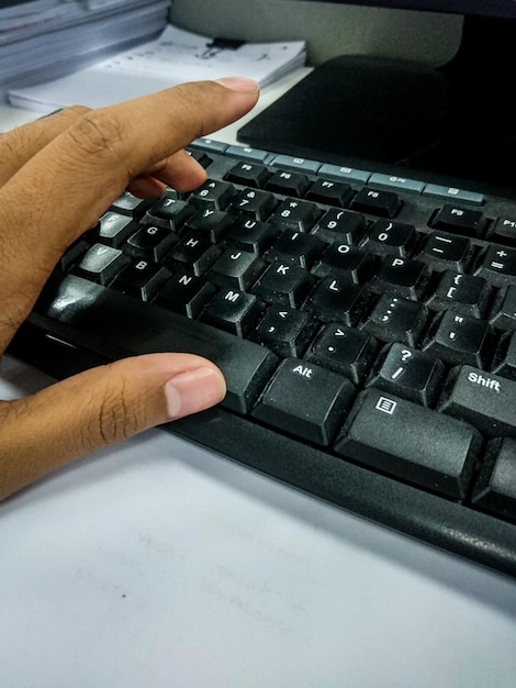 Zdjęcie przycięta ręka używająca klawiatury przy biurku