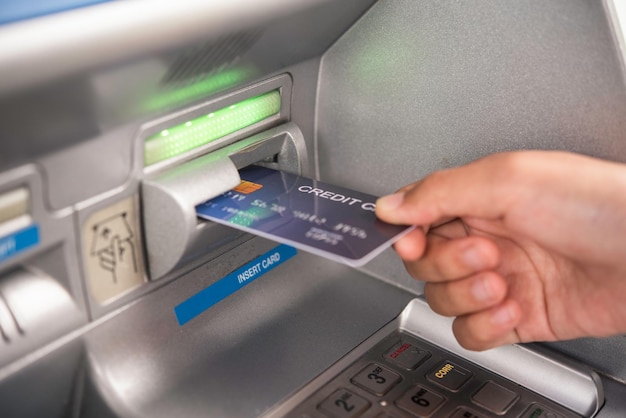 Przycięta ręka wkładająca kartę kredytową do bankomatu