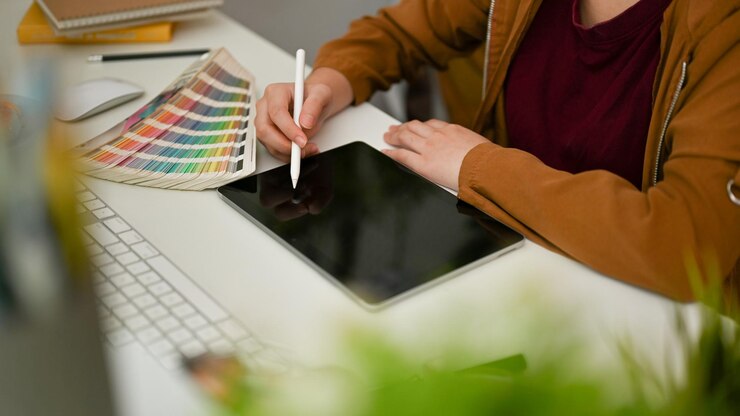 Przycięte Odnosząca sukcesy projektantka graficzna korzystająca z cyfrowego tabletu graficznego i pracująca przy biurku