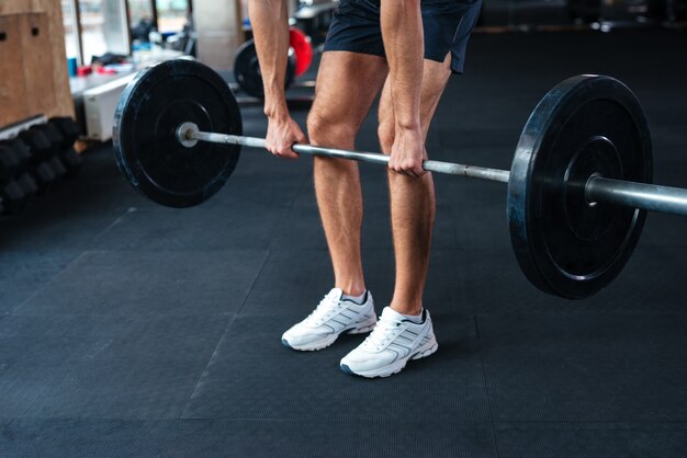 Przycięte portret człowieka fitness ze sztangą. wykonywanie ćwiczenia