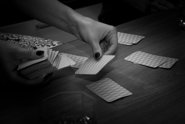 Zdjęcie przycięte ręce kobiety grającej w karty przy stole