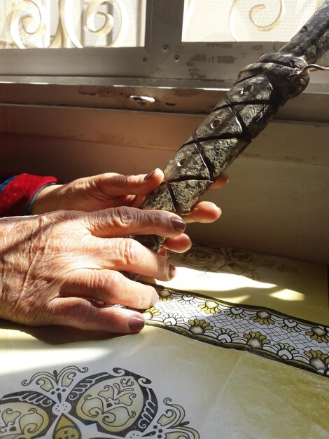 Zdjęcie przycięte ręce kobiety trzymającej stary miecz na łóżku w domu