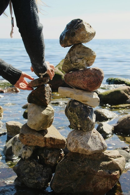 Zdjęcie przycięte ręce kobiety układającej kamienie na plaży