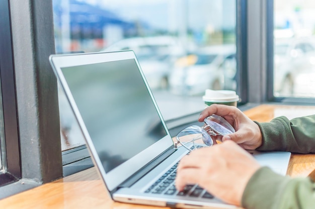 Zdjęcie przycięte ręce kobiety używającej laptopa przy stole