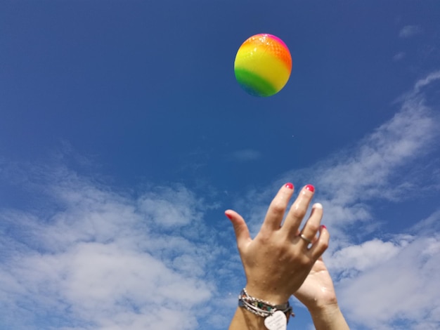Zdjęcie przycięte ręce łapią piłkę na chmurowym niebie