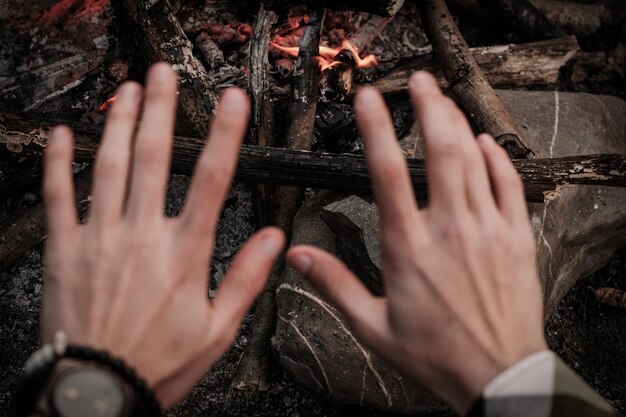 Przycięte ręce mężczyzny gestując przed ogniem obozowym