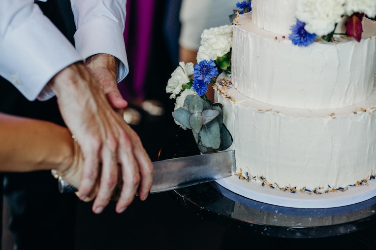 Zdjęcie przycięte ręce pary rzucającej tort ślubny