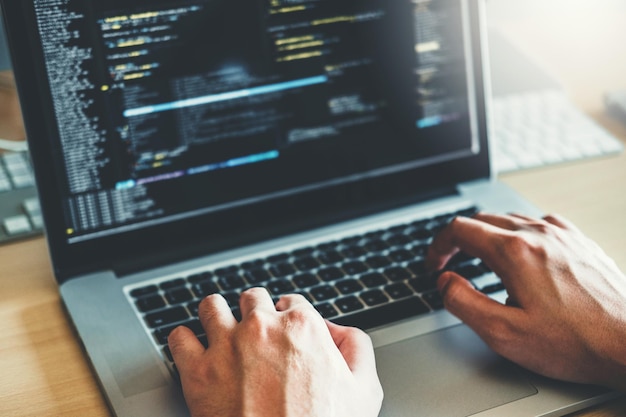 Przycięte ręce programisty komputerowego używającego laptopa na stole