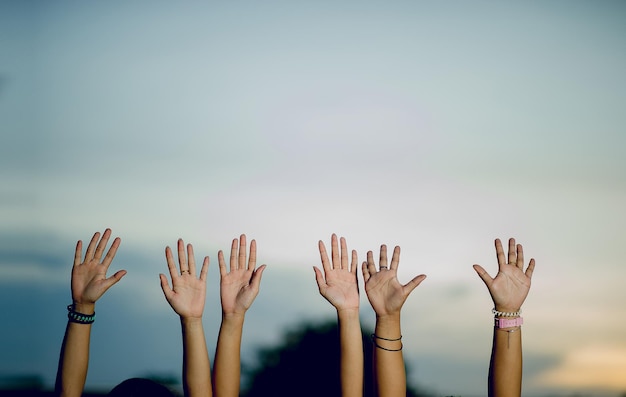 Przycięte ręce przyjaciółek z rękami podniesionymi do nieba podczas zachodu słońca