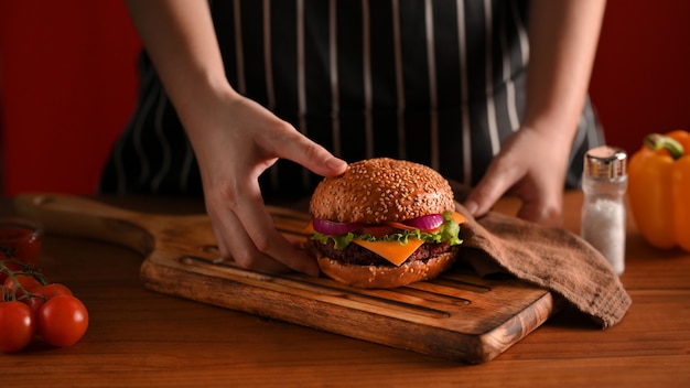 Przycięte Strzał Kobiety Kucharz Ręki Trzymającej Pyszne Grillowane Burgery Wołowe Miejsce Na Drewnianej Tacy, Aby Służyć W Restauracji