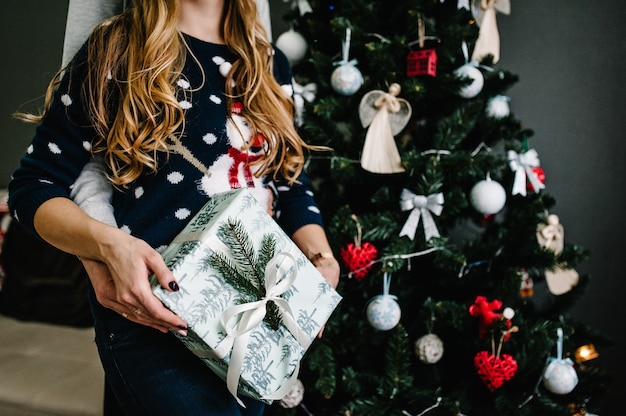 Przycięte Ujęcie Mężczyzny Zaskakującego Swoją Dziewczynę Prezentem Bożonarodzeniowym W Pobliżu Drzewa. Rodzina Daje Prezent, Night Xmas. Wesołych świąt I Wesołych świąt! Rodzina Wymieniająca Prezenty.