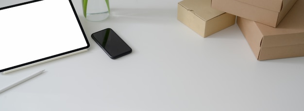 Przycięte ujęcie prostego stołu roboczego z tabletem, smartfonem, pudełkami i kopią