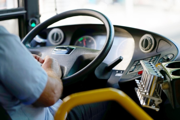 Przycięte zdjęcie kierowcy autobusu trzymającego kierownicę