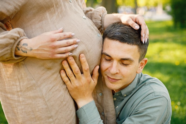 Przycięte zdjęcie mężczyzny przytulającego ciężarny brzuch żony w parku