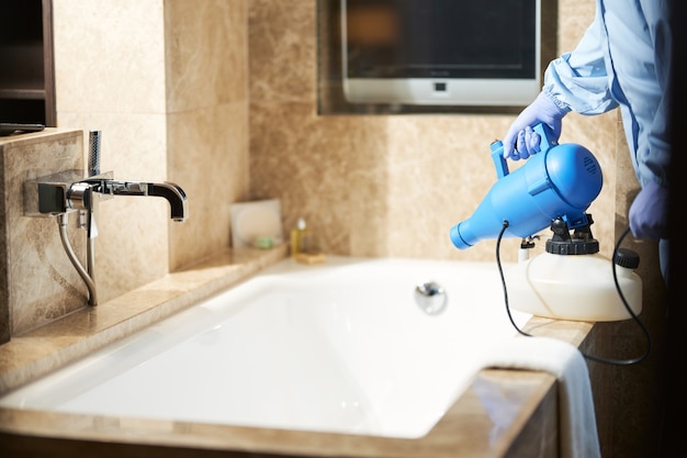 Przycięte zdjęcie mężczyzny używającego środka dezynfekującego, aby zapobiec ryzyku epidemii koronawirusa w łazience. Koncepcja koronawirusa i kwarantanny