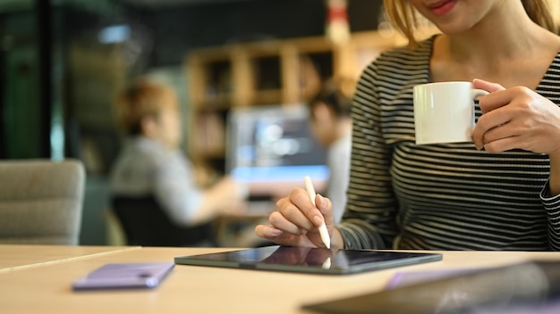 Przycięte zdjęcie młodej liderki zespołu przy użyciu cyfrowego tabletu, siedząc w biurze firmy zajmującej się oprogramowaniem