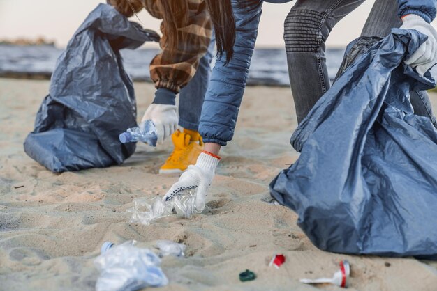 Przycięty obraz grupy wolontariuszy sprzątających linię plażową