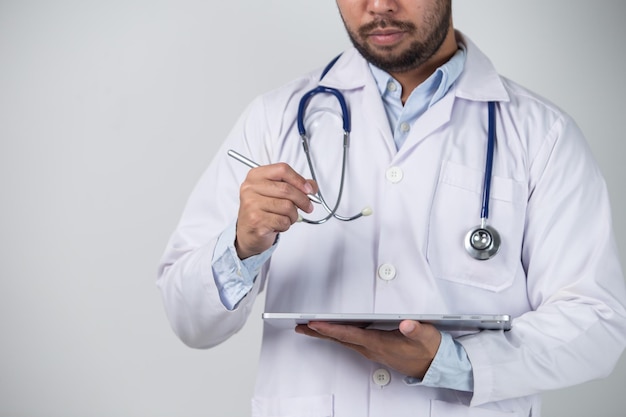 Przycięty obraz męskiego lekarza trzymającego cyfrowy tablet stojąc na białym tle