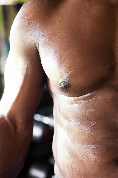 Przycięty obraz młodego afrykańskiego mokrego ciała sportowca po treningu