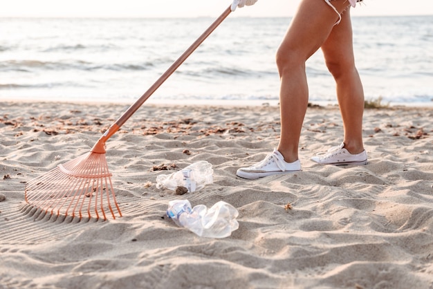Zdjęcie przycięty obraz młodej kobiety wolontariuszki sprzątającej plażę z plastikowych śmieci