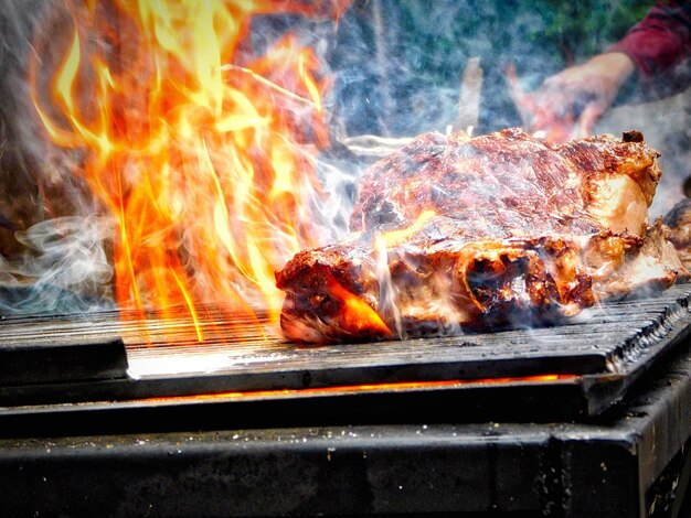 Zdjęcie przycięty obraz osoby grillującej kurczaka na grillu