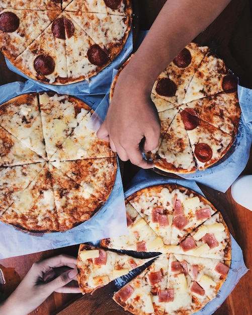 Zdjęcie przycięty obraz rąk trzymających pizzę na stole