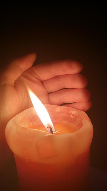 Zdjęcie przycięty obraz ręki osoby przez oświetloną świecę