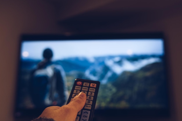 Zdjęcie przycięty obraz ręki trzymającej zdalny ster przed telewizorem