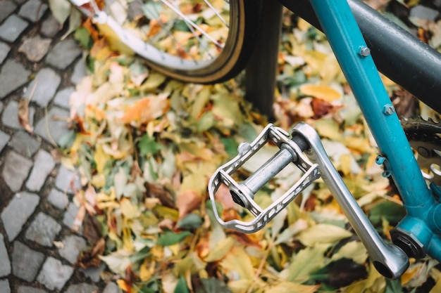 Zdjęcie przycięty obraz roweru zaparkowanego przez jesienne liście na chodniku