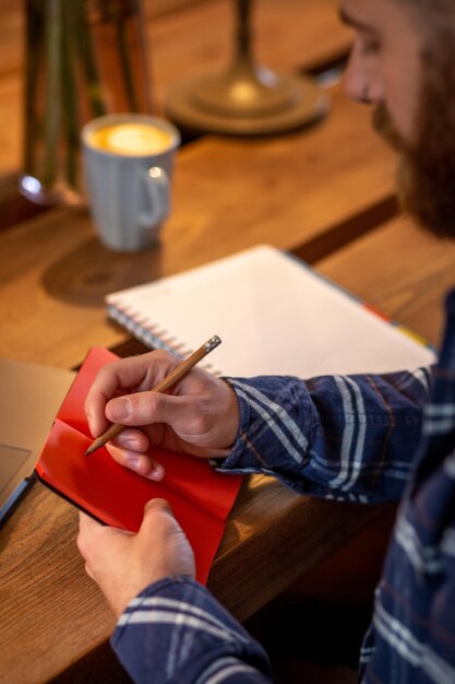 Przycięty obraz zwykłego biznesmena lub freelancera planującego swoją pracę na notebooku pracującym na laptopie c...