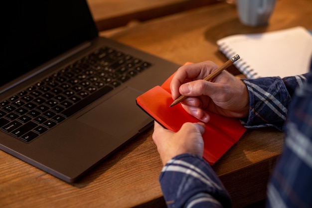 Przycięty obraz zwykłego biznesmena lub freelancera planującego swoją pracę na notebooku pracującym na laptopie c...