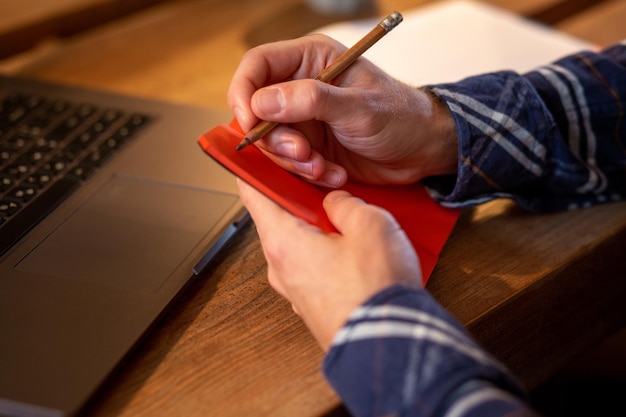 Przycięty obraz zwykłego biznesmena lub freelancera planującego swoją pracę na notebooku pracującym na laptopie c...