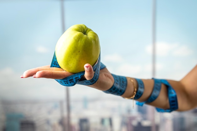 Przycięty portret trenera fitness z jabłkiem w dłoni i wstążką owiniętą wokół ramienia